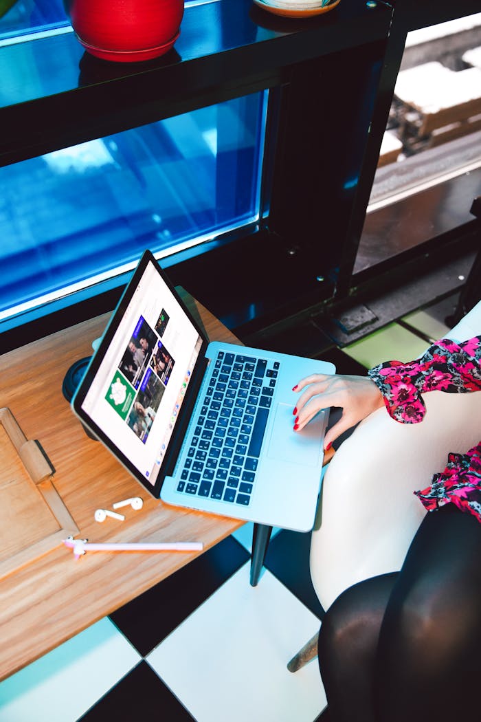 A woman uses a laptop at a stylish home workspace, blending technology with fashion.