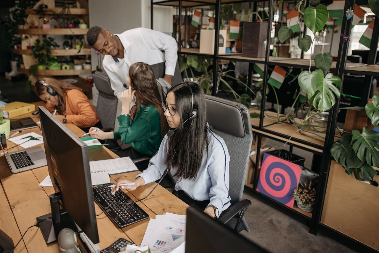 A diverse group of employees collaborating at computers in a modern office environment.